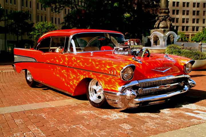 chevrolet 1957 rouge avec plein de petite flammes orange elle a également un blower