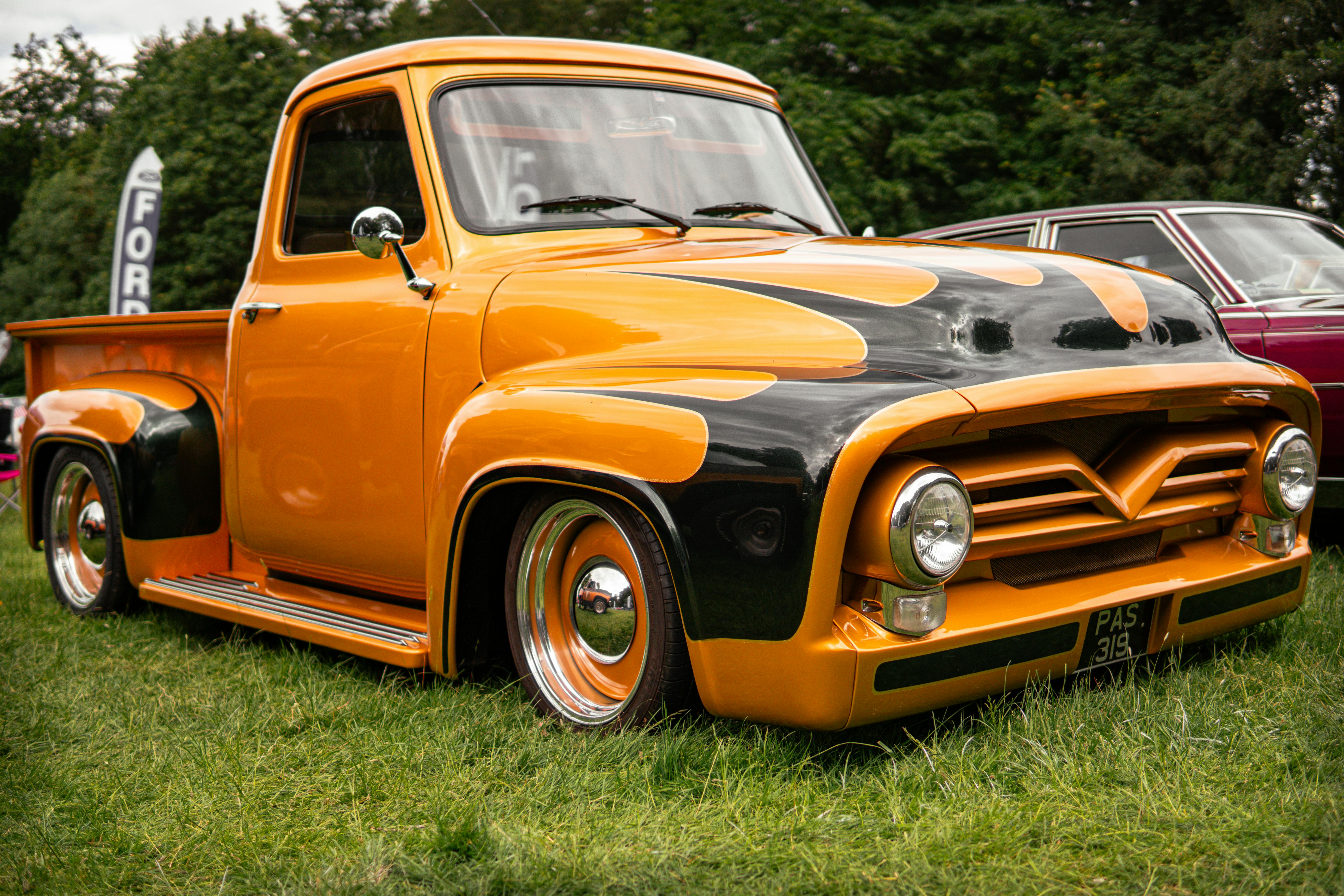 Ford F-100 Pickup orange avec vynile noire donnant l'impréssion d'etre tirer vers l'arrière a cause de la vitesse